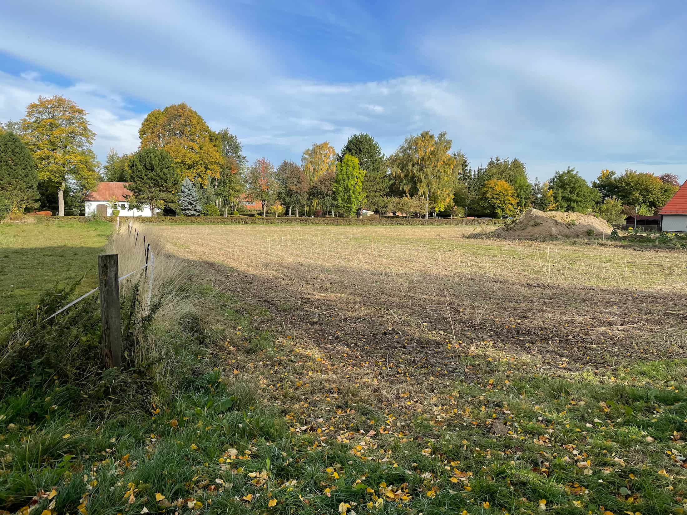 Luftaufnahme des Baugebiets Räbke mit freien Grundstücken, Erschließungsstraße und angrenzender Wohnbebauung in ländlicher Umgebung.